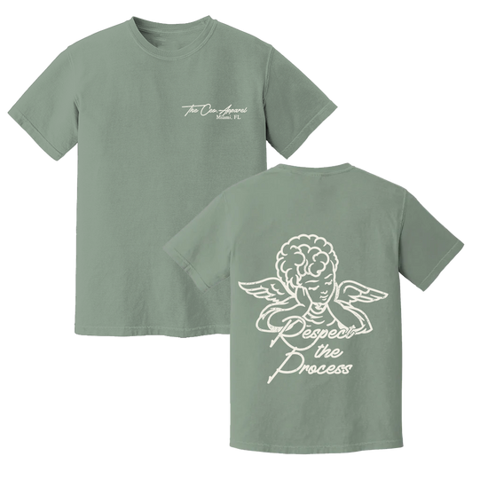 A sage green t-shirt with two views. The front features a small logo on the left chest that reads 'The CEO. Apparel Miami, FL' in white script. The back showcases a large white illustration of an angel with the phrase 'Respect the Process' written below.
